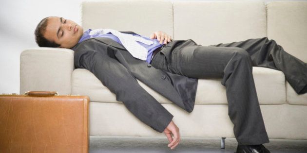 Indian businessman laying sleeping on sofa with briefcase