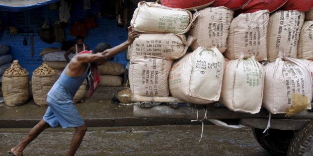 A labourer pushes a handcart loaded with sacks containing tea packets, towards a supply truck at a wholesale market in Kolkata, India, June 26, 2015. For years Indian businesses have lobbied for a nationwide sales tax, hoping to replace a chaotic structure that inflates costs and halts their trucks at state borders for duty payments, and to unify the country into one of the world's largest single markets. But after political compromises that finally got a goods and services tax (GST) bill before parliament, they have turned wary. Picture taken June 26. REUTERS/Rupak De Chowdhuri