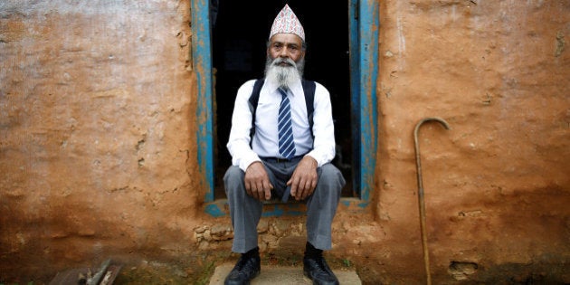 Durga Kami, 68, who is studying tenth grade at Shree Kala Bhairab Higher Secondary School, poses for a picture wearing his school uniform at the door of his one-room house in Syangja, Nepal, June 5, 2016. REUTERS/Navesh Chitrakar. SEARCH