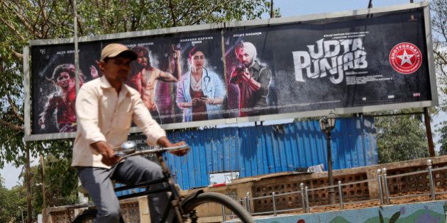 A man rides his bicycle past a poster of the movie