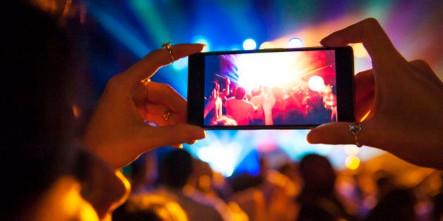 Woman taking a photo with phone at music event