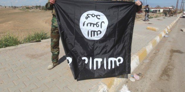 Iraqi Sunni and Shiite fighters pose for a photo with an Islamic State (IS) group flag in the Al-Alam town, northeast of the Iraqi city of Tikrit, on March 17, 2015 after recapturing the town from IS fighters earlier in the month. Loyalists had already failed three times to retake the nearby city of Tikrit, the hometown of Saddam Hussein, which was captured by IS last summer. AFP PHOTO / AHMAD AL-RUBAYE (Photo credit should read AHMAD AL-RUBAYE/AFP/Getty Images)