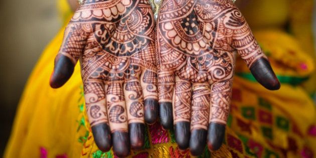 An Indain bride's hand with henna tattoos. An Indian bride showing her palms painted with a traditional mehandi design. The mehandi design is in sharp focus and no human face visible in the photograph.