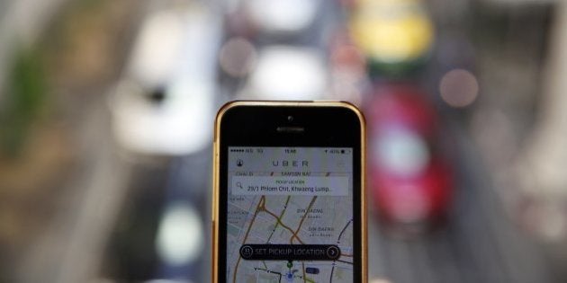 A phone running the Uber application is held above the traffic in central Bangkok December 10, 2014. Thailand has ordered U.S. online taxi booking company Uber to cease operations, on the same day taxi apps were banned in the Indian capital New Delhi where an Uber driver is under arrest for suspected rape. REUTERS/Damir Sagolj (THAILAND - Tags: SOCIETY SCIENCE TECHNOLOGY CRIME LAW TRANSPORT)