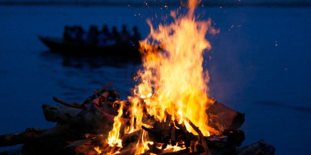 A tourist boat goes past the burning flames of a pyre at a cremation ground on the banks of river Ganges in Varanasi June 12, 2007. Hindus believe that dying in Varanasi and having their remains scattered in the Ganges allows their soul to escape a cycle of death and rebirth, attaining
