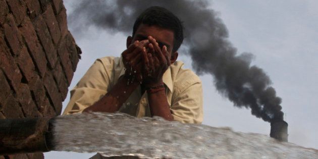 A labourer drinks water as smokes rise from a chimney of a brick factory at Togga village on the outskirts of the northern Indian city of Chandigarh December 6, 2009. India set a goal on Thursday for slowing the growth of its greenhouse gas emissions, the last major economy to offer a climate target four days before the start of U.N. talks on combating global warming. REUTERS/Ajay Verma (INDIA ENVIRONMENT SOCIETY) FOR BEST QUALITY IMAGE: ALSO SEE GF2E63C14JP01