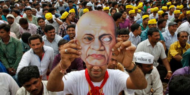 A Patidar or member of Patel community holds a mask of Indian freedom fighter and first Home Minister of Independent India Sardar Vallabhbhai Patel as he participates in a rally in Ahmadabad, India, Tuesday, Aug. 25, 2015. Members of Patel community held a rally Tuesday demanding reservations under the Other Backward Class (OBC) quota. (AP Photo/Ajit Solanki)