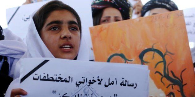 An Iraqi Yazidi woman holds a placards during a protest outside the United Nations (UN) office in the Iraqi city of Arbil, the capital of the autonomous Kurdish region, on August 2, 2015 in support of women from their community who were kidnapped last year in the Sinjar region by the Islamic State (IS) group jihadists. In 2014, the jihadists massacred Yazidis, forced tens of thousands of them to flee, captured thousands of girls and women as spoils of war and used them as sex slaves. AFP PHOTO / SAFIN HAMED (Photo credit should read SAFIN HAMED/AFP/Getty Images)