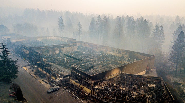 In this Nov. 15, 2018 photo, smoke hangs over the scorched remains of Old Town Plaza following the devastating wildfire in Pa