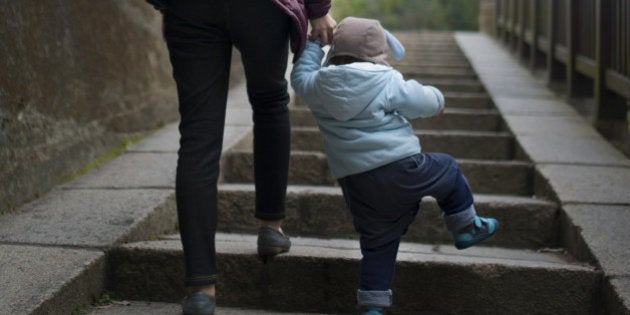 Rear view 18 months child climbing on stairs with mother