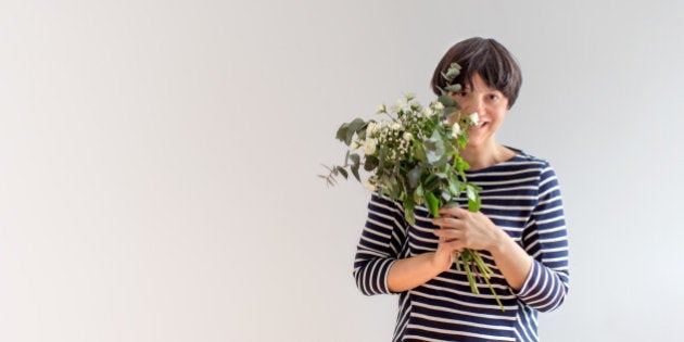 Woman peaking behind bouquet of white roses