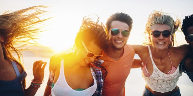 Friends dancing on beach in sunset