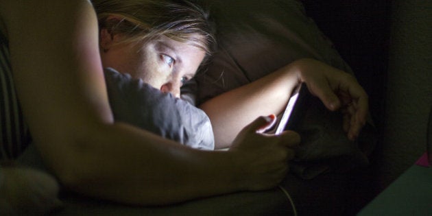 Caucasian woman using cell phone in bed