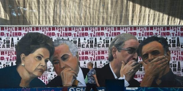 A woman walks past a mural depicting the president of the Brazilian lower house of Congress Eduardo Cunha (2-R) speaking with the president of the Brazilian Social Democracy Party (PSDB) Aecio Neves (R) as if they were conspiring against Brazilian President Dilma Rousseff (L), who is depicted speaking with Vice-President Michel Temer, at Paulista Avenue in Sao Paulo, Brazil on April 19, 2016.Brazil woke Monday to deep political crisis after lawmakers authorized impeachment proceedings against President Dilma Rousseff, sparking claims that democracy was under threat in Latin America's biggest country. / AFP / NELSON ALMEIDA (Photo credit should read NELSON ALMEIDA/AFP/Getty Images)