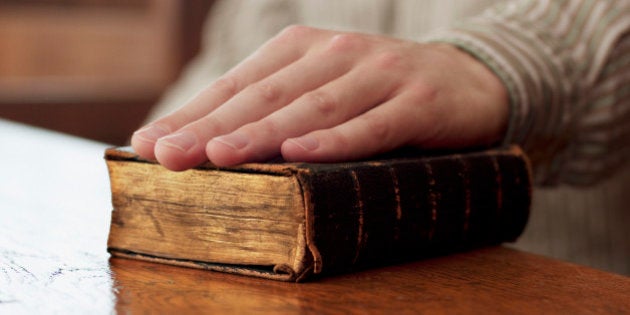 Hand of witness on Bible in courtroom