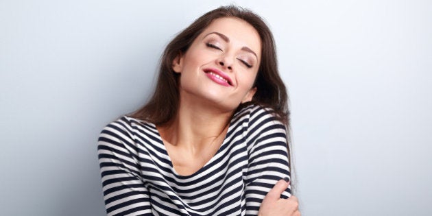 Happy young casual woman hugging herself with natural emotional enjoying face. Love concept by yourself