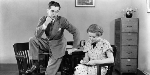 1940s BUSINESSMAN LEANING AGAINST DESK WITH FOOT PROPPED ON CHAIR LEERING OGLING SECRETARY SITTING NEXT TO HIM TAKING NOTES (Photo by H. Armstrong Roberts/ClassicStock/Getty Images)