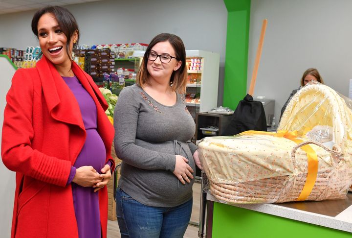 Meghan, Duchess of Sussex presents Angela Midgley with a Moses basket at "Number 7", a "Feeding Birkenhead" citizens supermarket and community cafe, in Birkenhead, Britain on Jan. 14,