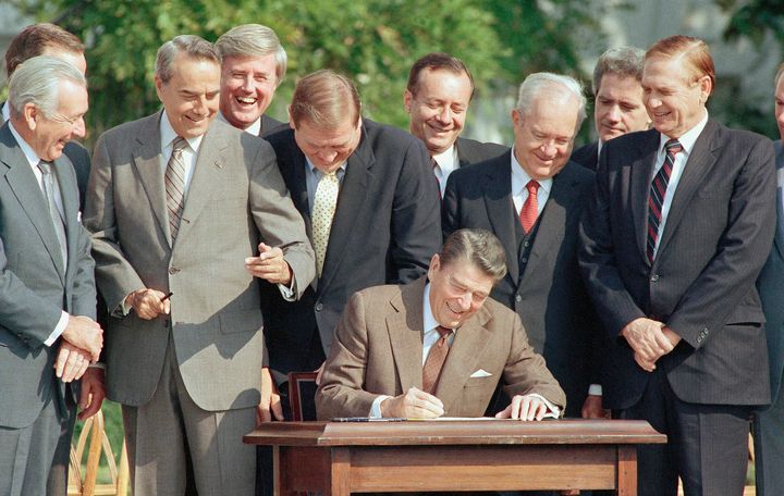 Lawmakers watch President Ronald Reagan sign into law the 1986 Tax Reform Act on the White House South Lawn on Oct. 22, 1986. From left, are: Senate Majority Leader Robert Dole of Kansas, Rep. Raymond McGrath, R-N.Y.; Rep. Dan Rostenkowski, D-Ill., Rep. Frank Guerini, D-N.J.; Sen. Russell Long, D-La.; Rep. William Coyne, D-Pa., and Rep. John Duncan, R-Tenn. 