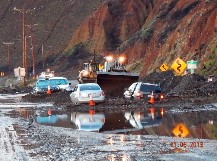 In this Sunday, Jan. 6, 2019 photo, California Department of Transportation (CalTrans) crews work to clear mud and rocks that tumbled onto Pacific Cost Highway in Malibu, Calif. 