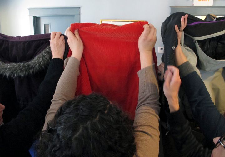 People hold up coats to block harasser Max Misch from view at Monday's press conference.