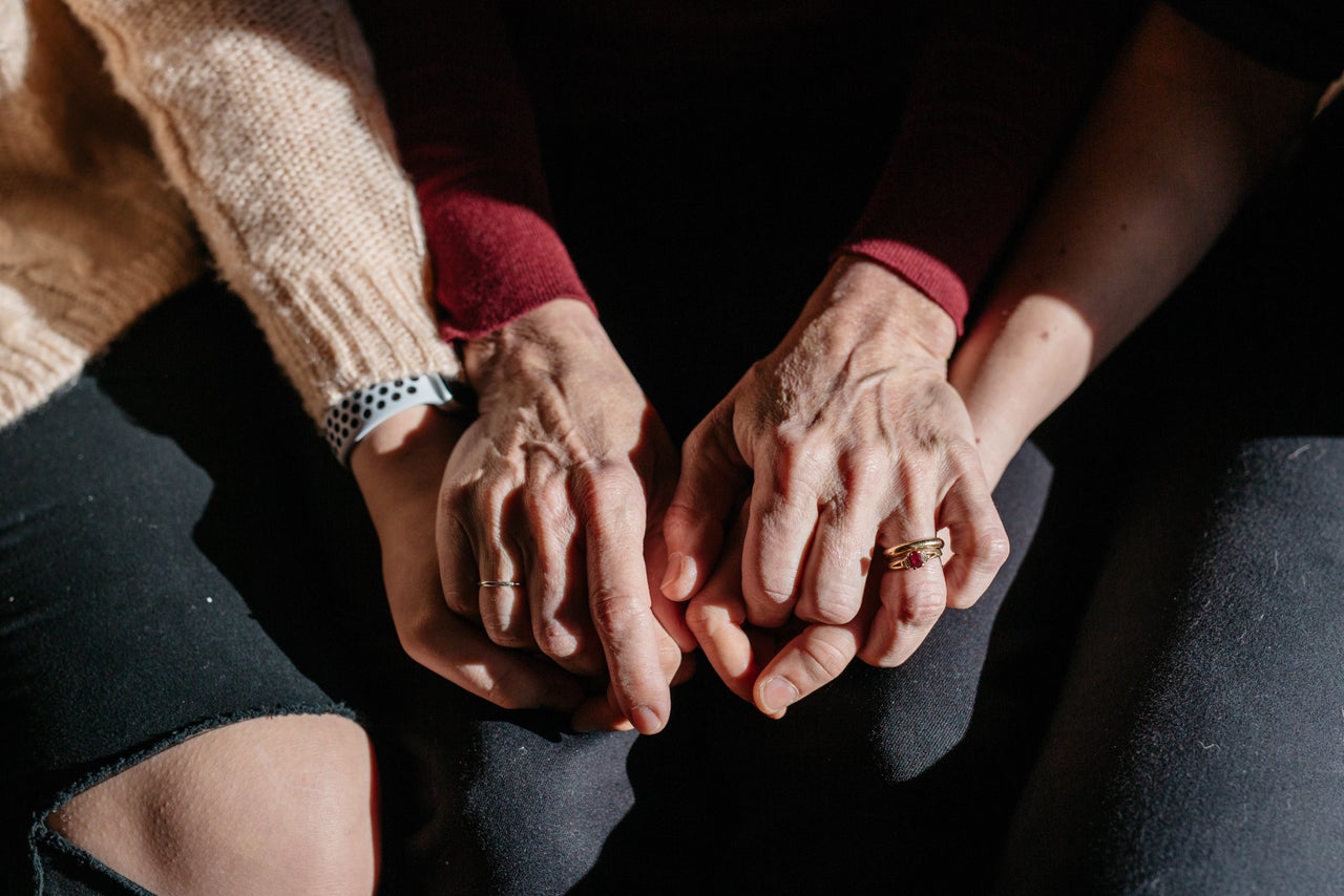 Suzanne Thomashow (center), holds the hands of her daughers Amanda (right) and Jessica (left), Nassar survivors inside their home in Lansing, Michigan.