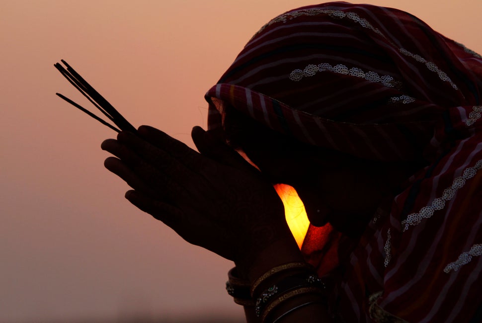 A woman devotee offers prayers to the setting sun on the 20th anniversary of the Babri mosque demolition in Ayodhya.