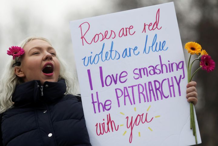 A demonstrator at a women's march in London on Jan. 19, 2019, holding a sign reading, "Roses are red, violets are blue, I love smashing the patriarchy with you."