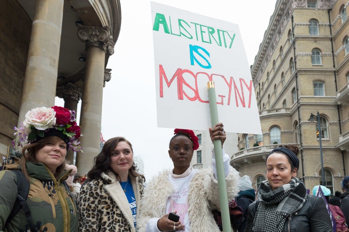 Demonstrators at a women's march in London, holding a sign reading, "Austerity is misogyny."