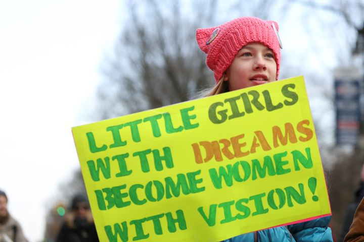 A girl at the Women's March in New York City holds a sign reading, "Little girls with dreams become women with vision!"