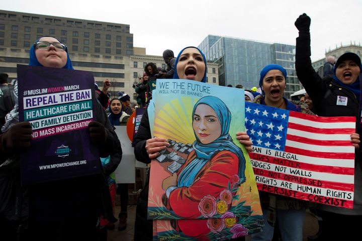 A group of demonstrators holds posters at the Women's March in Washington, D.C., including a sign featuring a woman wearing a hijab with the caption, "We the future will not be banned."
