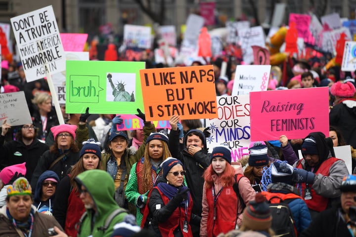 Participants in the Women's March in Washington, D.C., holding numerous signs, one of which reads, "I like naps but I stay woke."