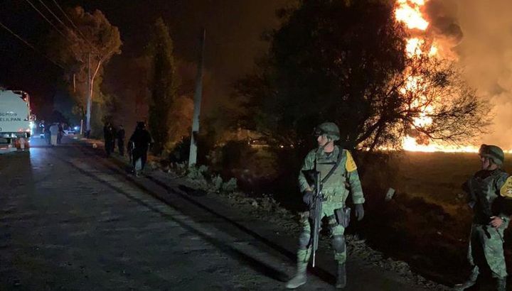 Military personnel watch as flames engulf an area after a ruptured fuel pipeline exploded in Mexico.