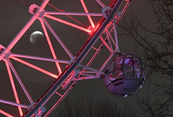 The "super blood wolf moon" is seen in partial eclipse in the skies behind the London Eye wheel in London.