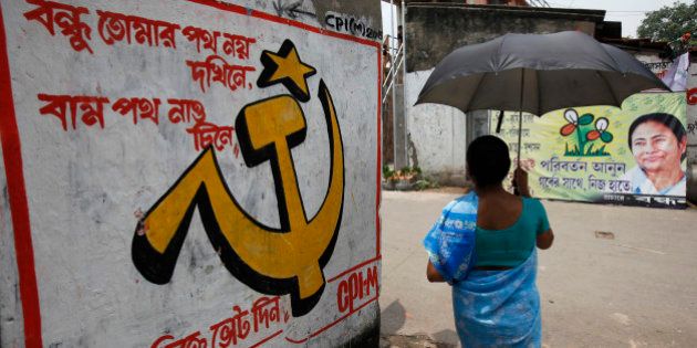 A woman carrying an umbrella walks past political murals and posters in Kalighat district, the neighbourhood where Trinamool Congress leader Mamata Banerjee lives, in Kolkata May 12, 2011. The murals feature slogans in support of the the Marxist Left Front (L) and Trinamool Congress with a portrait of Banerjee (R). Exit polls show the 56-year-old Banerjee will win a landslide vote when ballots are counted on Friday to become the next leader of this state of 90 million, a population equivalent to Germany. REUTERS/Danish Siddiqui (INDIA - Tags: POLITICS ELECTIONS)