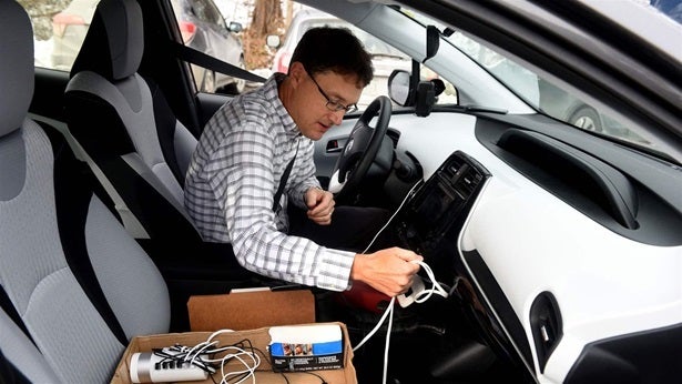 Corey Chase, a telecommunications analyst with Vermont’s Department of Public Service, checks his power cord in Royalton, Vermont. For nearly two months, Chase drove eight to 10 hours a day for a mile-by-mile project to map mobile broadband coverage throughout Vermont.