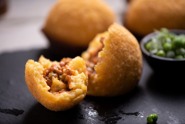 Arancini é um salgado italiano recheado de risoto.