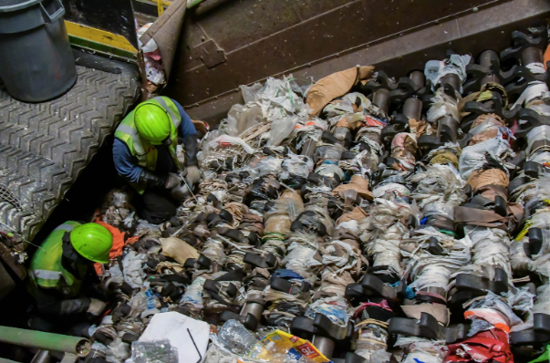 Workers at a Waste Management Inc. recycling facility try to detangle dozens of plastic bags stuck in the sorting equipment. The plant has to suspend operations several times a day while the workers fix the problem. 