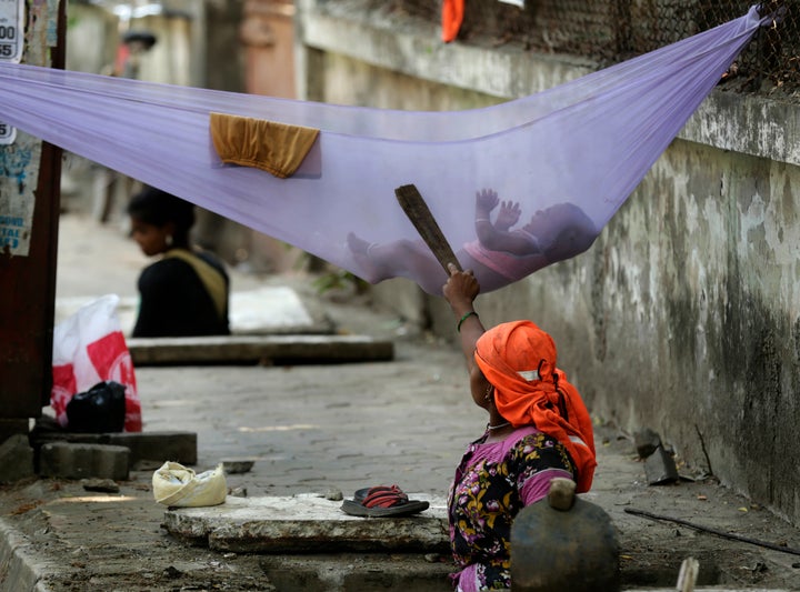 A woman labourer pacifies her child while cleaning a manhole on a sidewalk in Mumbai. The number of poor people in India is disputed, but the existence of a stubbornly persistent poverty on a substantial scale is not.