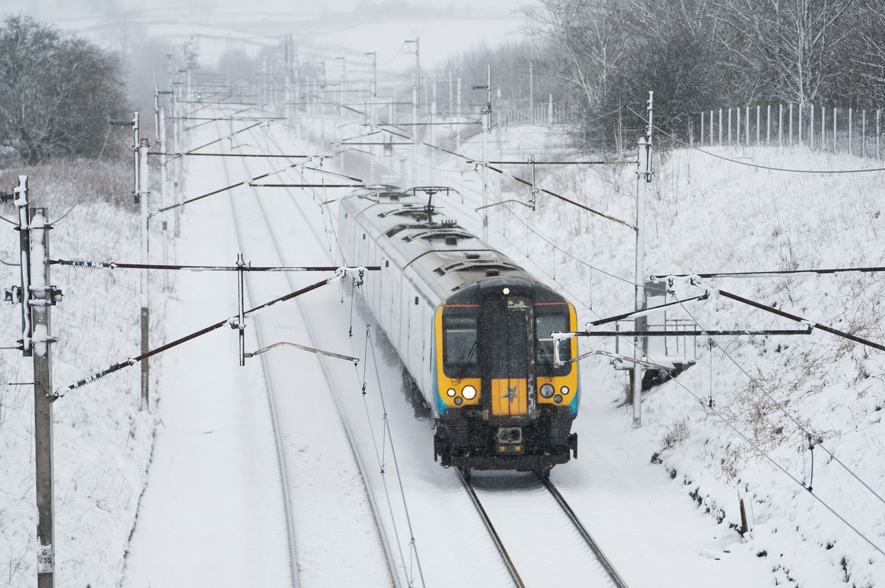 A train travels through snow on the West Coast Mainline in Cumbria.
