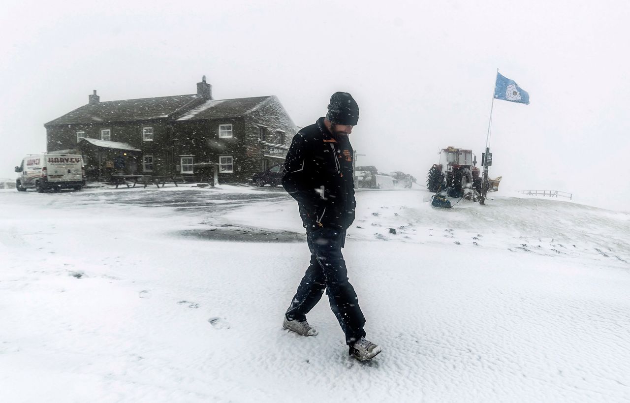 A man walks near the Tan Hill Inn in North Yorkshire as snow falls across Britain.