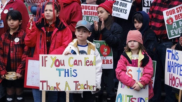 Elementary school students Capri Mac, right, and her brother Sawyer, second from right, support teachers during a citywide st