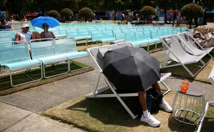 Spectators protect themselves from the heat with umbrellas as they watch tennis on a large video screen at the Australian Open tennis championships in Melbourne on Friday.