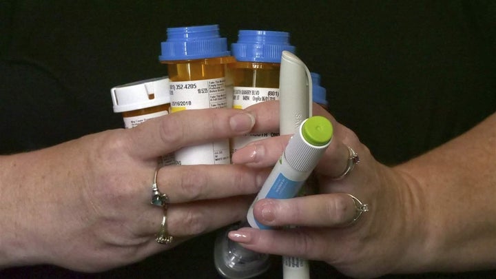 A woman with diabetes holds her prescriptions in her Sandy, Utah, home. She has had to change health insurance plans three ye