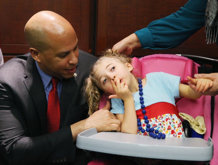 Sen. Cory Booker comforts 4-year-old Morgan Hintz, who suffers from a rare form of epilepsy, during a news conference on