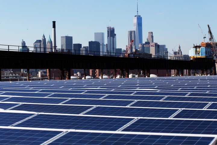 The Manhattan skyline peers over a rooftop covered with solar panels at the Brooklyn Navy Yard in New York.