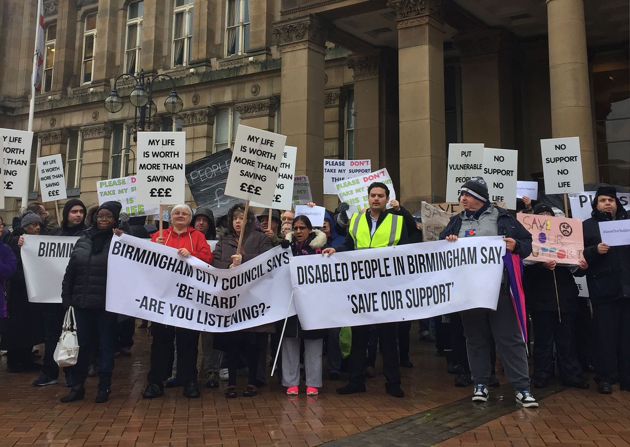Protestors in Birmingham wave placards objecting to cuts to council services