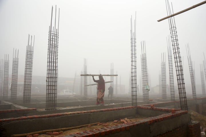 A woman carries building materials at a construction site in the morning smog near New Delhi, India.