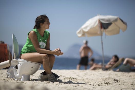 水の汚染に抗議するため、ビーチで便器に座る女性（2014年、ブラジル・リオデジャネイロ）
