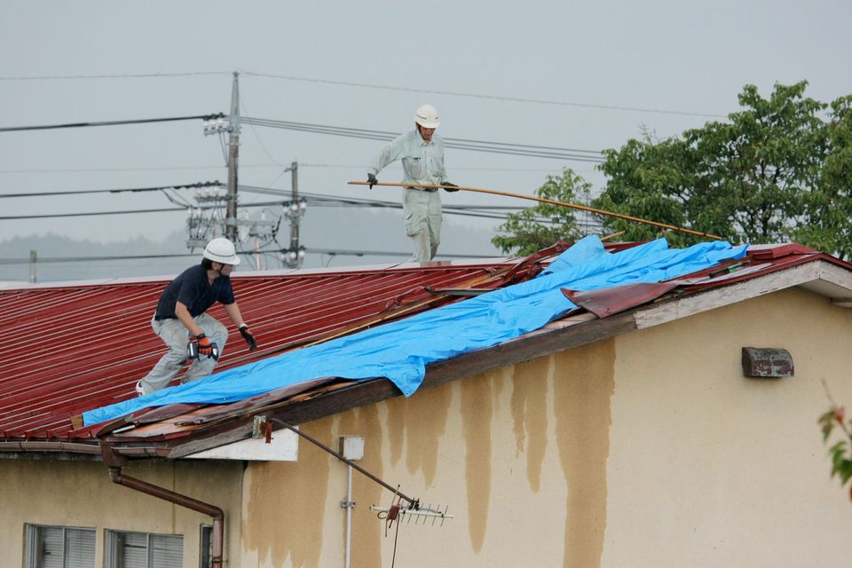 竜巻・屋根を補修する男性
